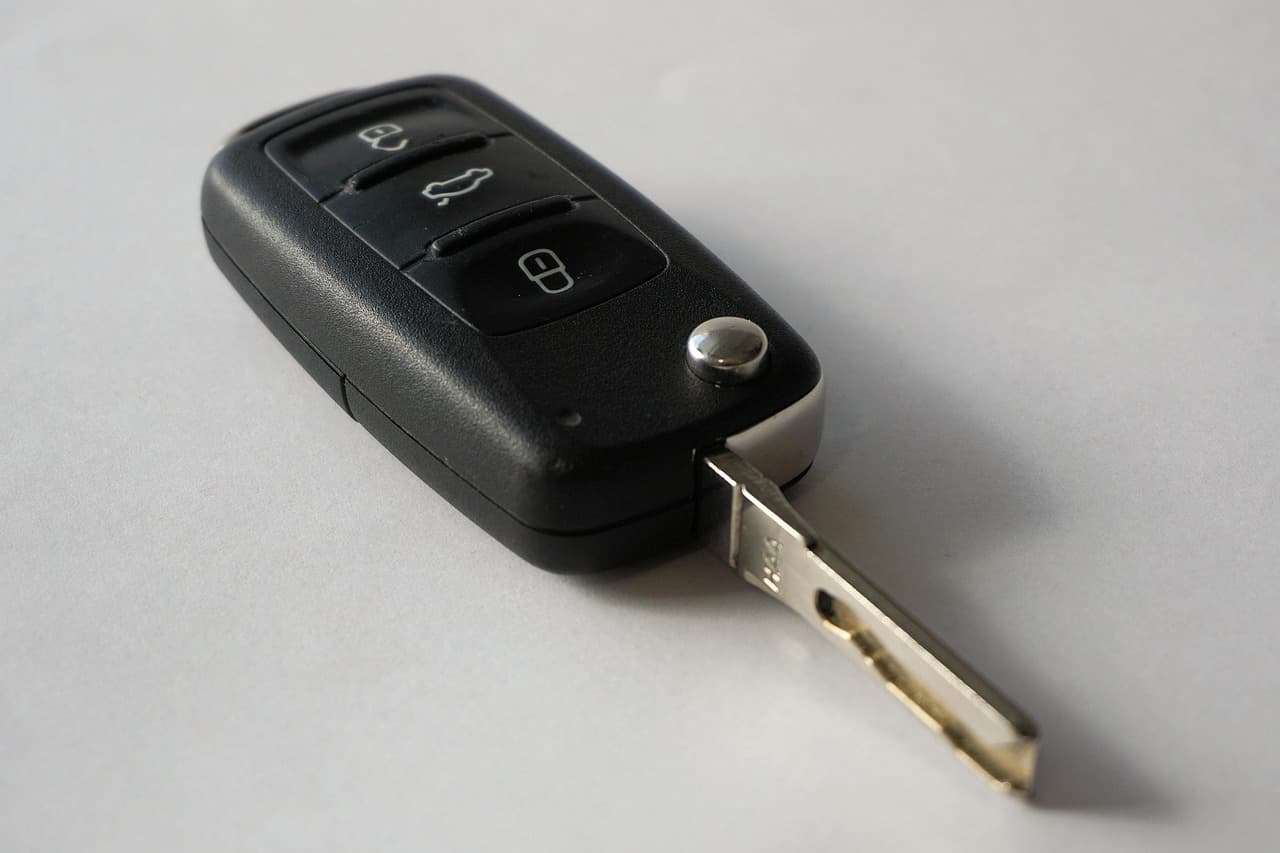 A black flip car key with three remote buttons, blade folded out