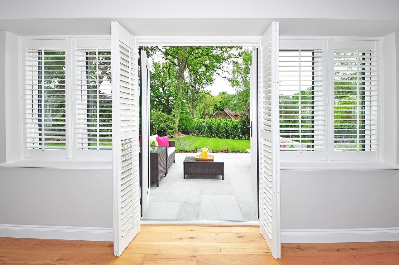 White French doors standing open from a bright room onto a garden patio